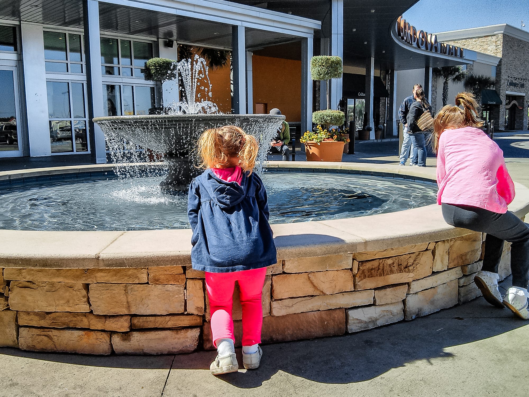 Two young girls seen playing from behind at the fountain at Cordova Mall.